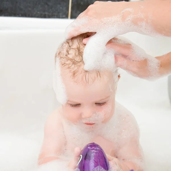 Mãe lavar o cabelo do bebê no banho . — Fotografia de Stock
