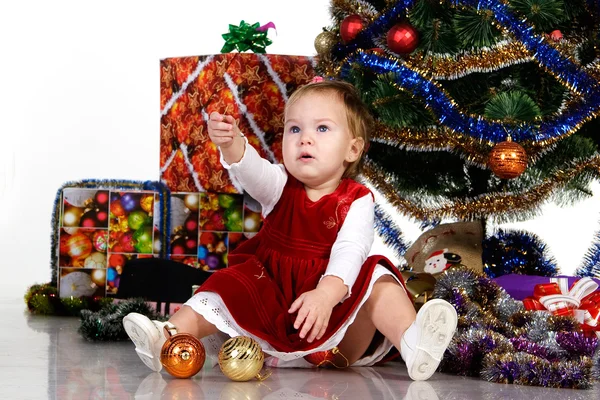 Bambino seduto sotto un albero di Natale Foto Stock