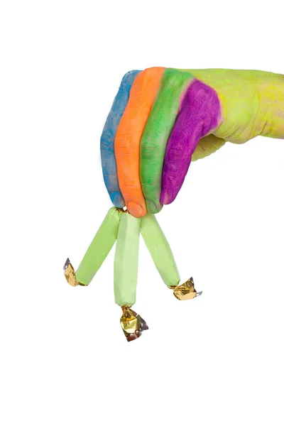 Main colorée tient ou donne trois bonbons verts — Photo