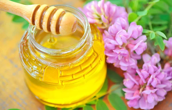 玻璃瓶里装满蜂蜜和棒子 — 图库照片