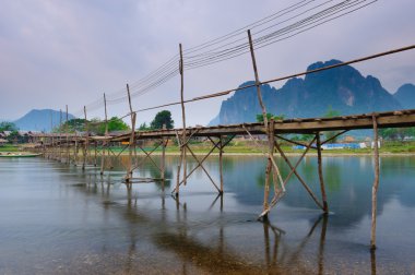 Wood bridge over river song to riverside guesthouse, Vang vieng, clipart