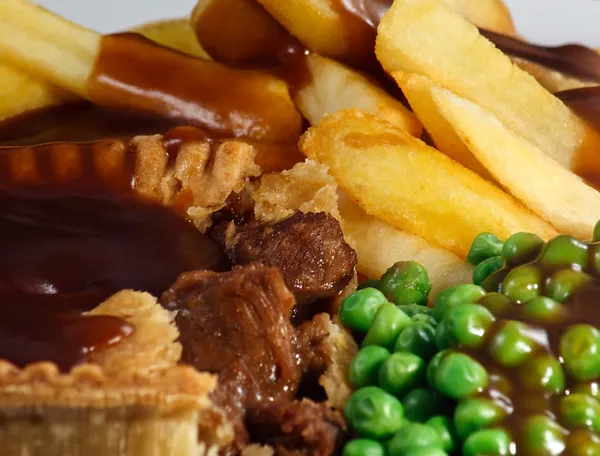 Close up of Steak Pie and chips with peas and gravy. — Stock Photo, Image