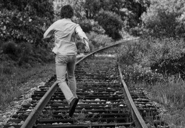 Boy running down the railroad tracks