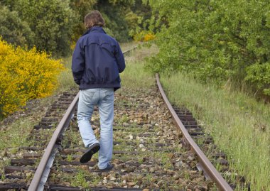 Boy walking down the railroad tracks