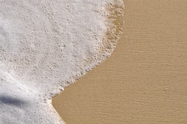 Sfondo spiaggia con sabbia e schiuma dal mare dell'oceano — Foto Stock