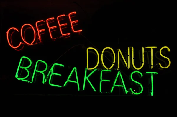 Káva koblihy snídaně neonový nápis — Stock fotografie