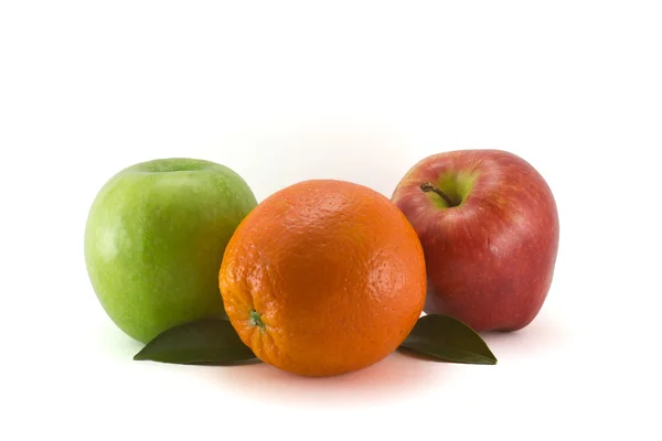 Апельсин с листочками и двумя яблоками — стоковое фото