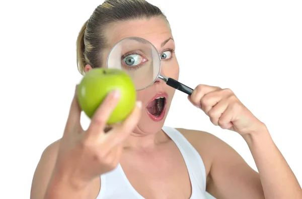 Υγιή Μπλόντι ευτυχισμένη γυναίκα βλέποντας πράσινο μήλο με ένα magnifyin — Φωτογραφία Αρχείου