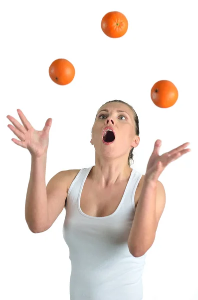 Здоровая красивая женщина жонглирует апельсинами на белой спине — стоковое фото