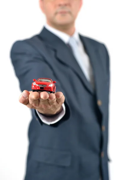 Empresário está segurando carro de brinquedo vermelho — Fotografia de Stock