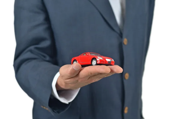 Empresário segurando um carro de brinquedo em sua mão — Fotografia de Stock