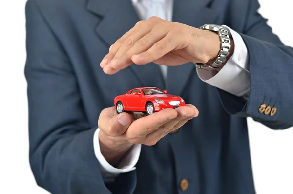 Empresario sosteniendo un coche de juguete en su mano — Foto de Stock