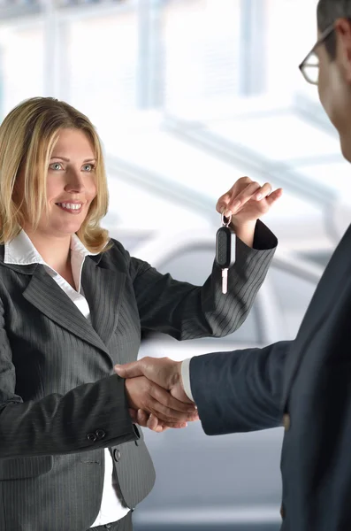 Geschäftsfrau übergibt Schlüssel an Geschäftsmann — Stockfoto