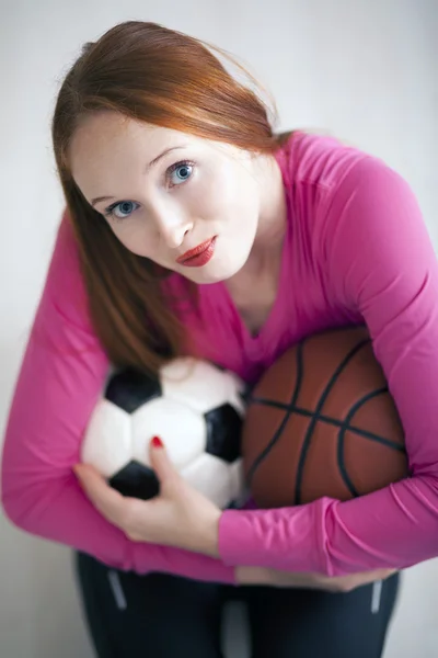 Hermosa chica rubia sosteniendo pelotas de fútbol y baloncesto —  Fotos de Stock