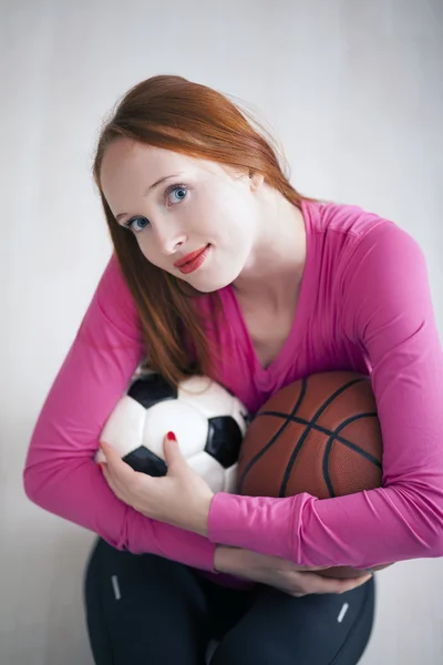 Красивая блондинка держит футбольные и баскетбольные мячи — стоковое фото