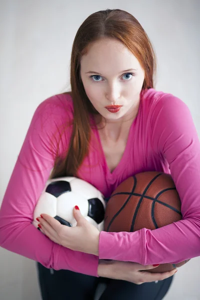 Beautiful blond girl holding soccer and basketball balls — Stockfoto
