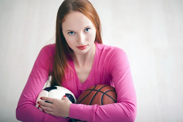 Menina loira bonita segurando bolas de futebol e basquete — Fotografia de Stock