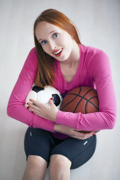 Όμορφη ξανθιά κοπέλα που κρατούν μπάλες ποδοσφαίρου και μπάσκετ — Φωτογραφία Αρχείου