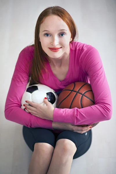Hermosa chica rubia sosteniendo pelotas de fútbol y baloncesto —  Fotos de Stock