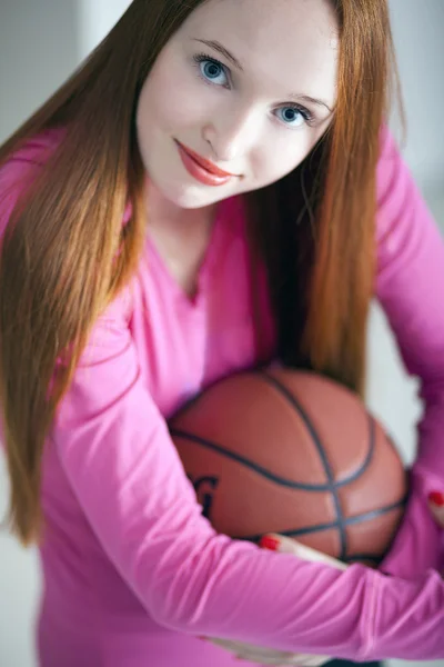 Menina de cabelos longos bonita segurando uma bola de cesta e sentado — Fotografia de Stock