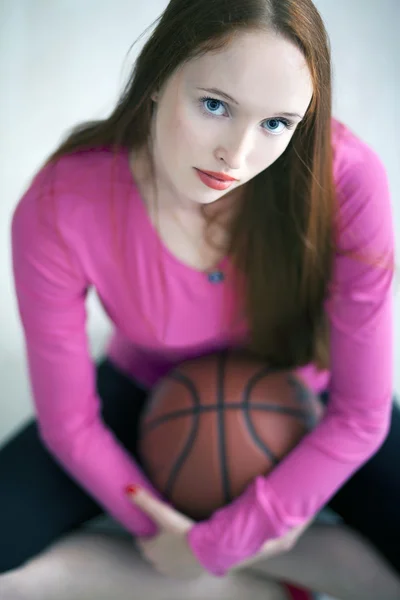 Schöne langhaarige Mädchen hält einen Basketballkorb und sitzt — Stockfoto