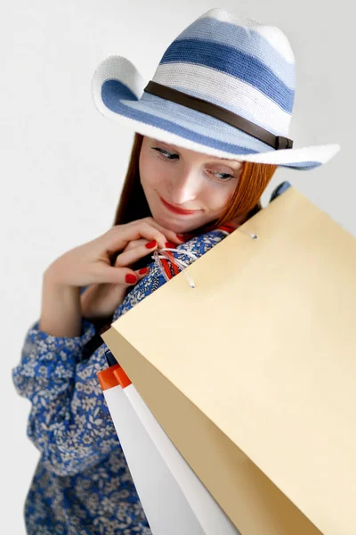 Långhåriga kvinna håller papperspåsar med inköp — Stock fotografie