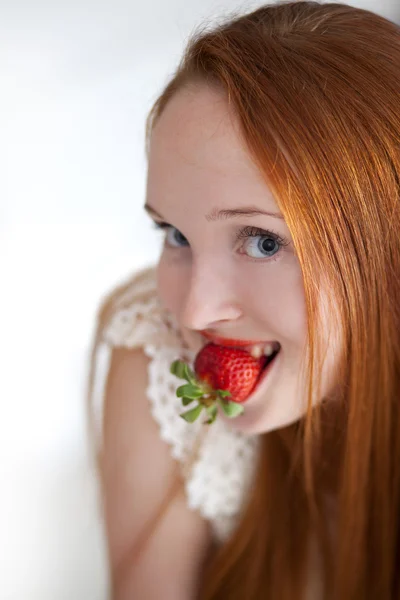Jeune belle femme aux cheveux longs mangeant des fraises mûres — Photo