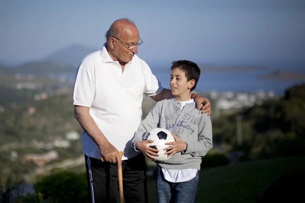 Маленький мальчик со стариком держит футбольный мяч — стоковое фото