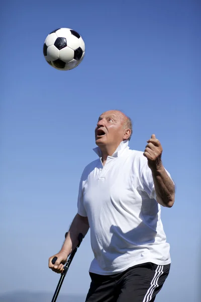 Pensionerad fotbollsspelare med käpp till chef för en soccerball — Stockfoto