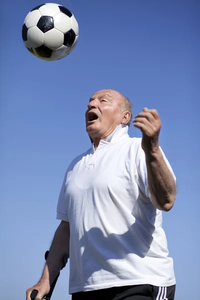 Fußballspieler im Ruhestand mit Gehstock zum Fußballköpfen — Stockfoto