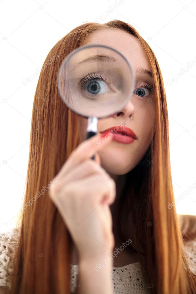 Young beautiful female looking through a magnifying glass