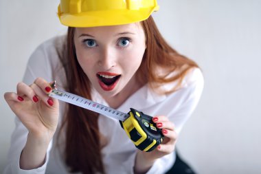 Girl holding a tape measure and wearing a safety hat clipart