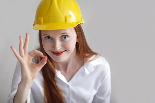 Langharige gelukkig meisje met gele helm het okey teken weergegeven: — Stockfoto