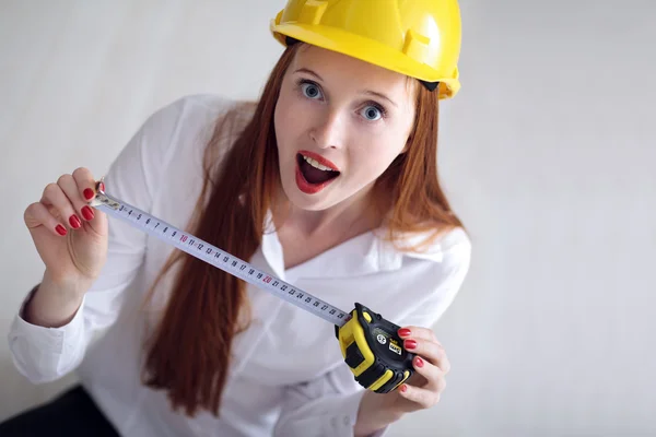 Woman holding a tape measure and wearing a safety hat — Stock Photo, Image