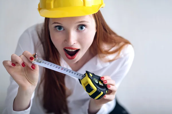 Girl holding a tape measure and wearing a safety hat — Stock Photo, Image