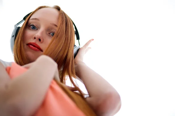 Рыжая девушка с длинными волосами, слушающая музыку в наушниках — стоковое фото