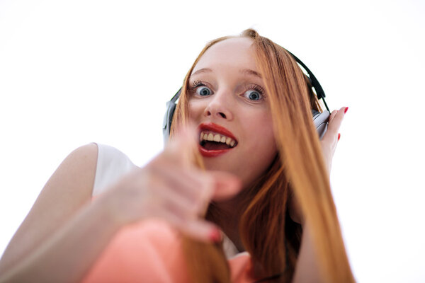 Long haired red headed girl with headphones listening to music