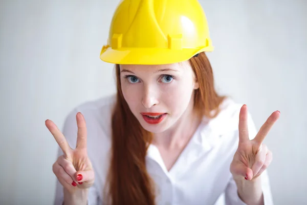 平和の記号を示す黄色のヘルメットを持つ若い美しい女性 — ストック写真