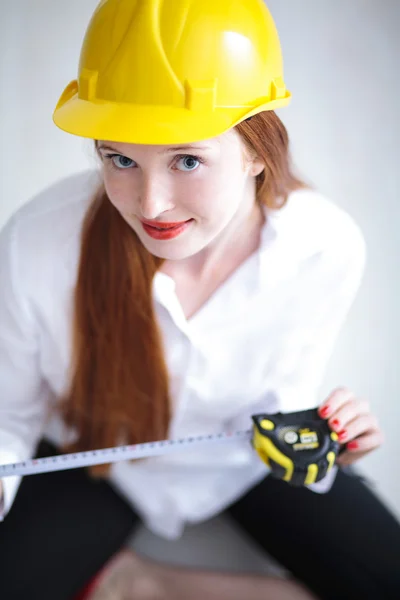 黄色いヘルメットの巻尺を保持するいると若い美しい女性 — ストック写真