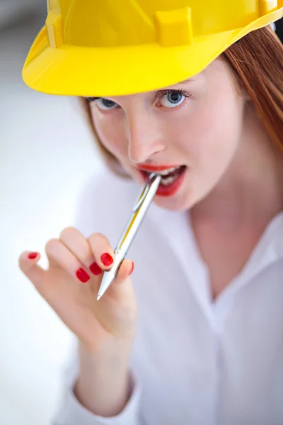 Long haired red headed woman holding a pen and wearing a safety — Stock Photo, Image