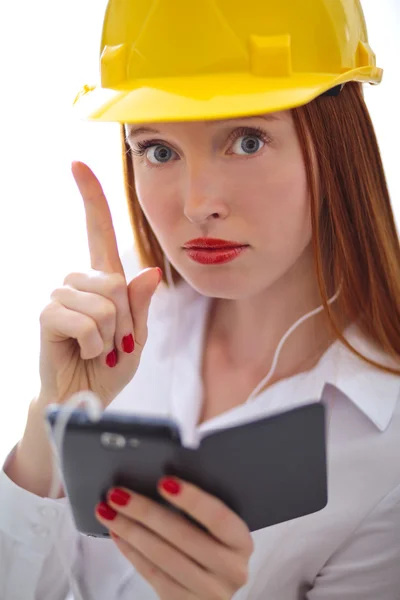 Jonge mooie vrouw met gele helm met behulp van een mobiele telefoon — Stockfoto