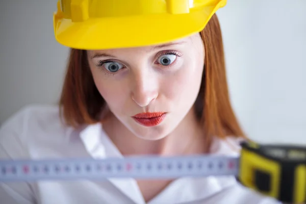 Young beautiful female with yellow helmet holding a tape measure — Stock Photo, Image