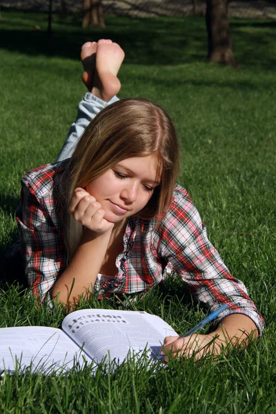 stock image Blond girl reading on the grass