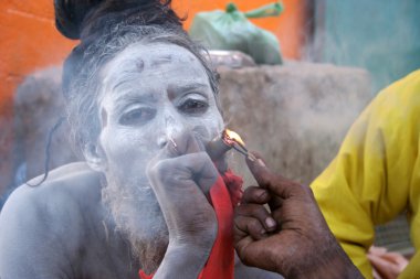 Hintli Sadhu, Ganj nehrinin kıyısında Chillum 'unu aydınlatıyor. Varanasi, Uttar Pradesh, Hindistan 'da, Ocak 2008' de çekildi..