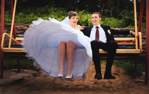 Bride and groom swing on a swing — Stock Photo, Image