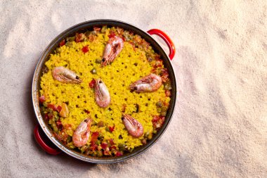 Paella over the sand of the beach clipart