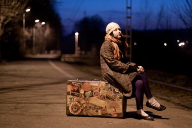 paltolu bir tren istasyonu bavula oturan kız