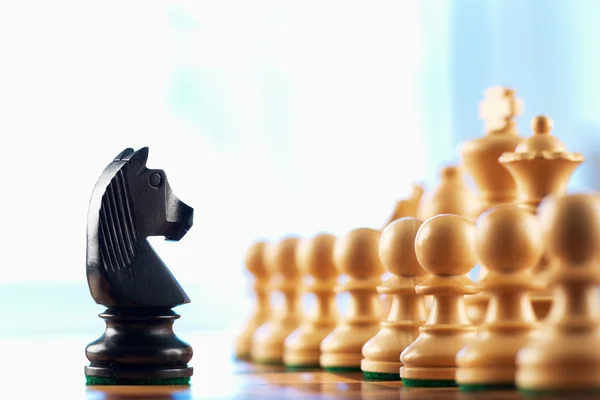 Chess black knight challenges white pawns — Stock Photo, Image