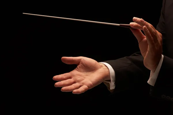 Director dirigiendo una orquesta aislada sobre fondo negro — Foto de Stock