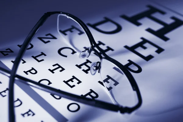 Glasses and eytest chart differential focus blue tone — Stock Photo, Image